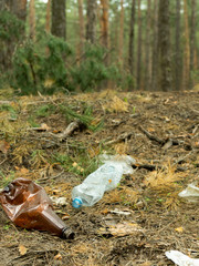 Empty plastic bottle in the form of garbage in the forest thrown by man. The concept of environmental pollution by human life products.
