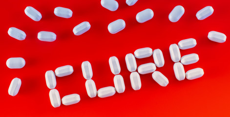 Cure word written with medicine pills on red background. Healing, remedy, treatment concept.