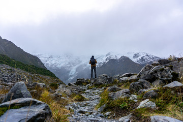 A man hiking mount cook under cloudy sky in New Zealand