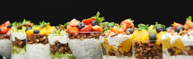 selective focus of fresh granola with fresh fruits and berries isolated on black, panoramic shot