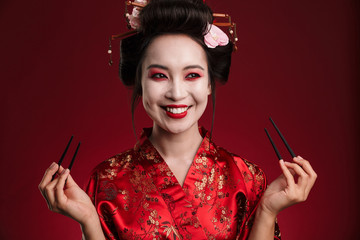 Obraz premium Image of beautiful geisha woman in japanese kimono holding chopsticks