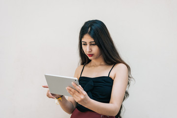 One Indian female girl holding and swiping touch screen mobile device with her right index finger