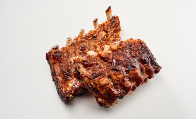 Two portions of grilled marinated ribs on white
