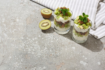 fresh granola with kiwi and yogurt on grey concrete surface with striped napkin