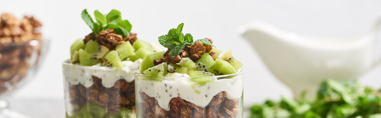 selective focus of fresh granola with kiwi and yogurt isolated on grey