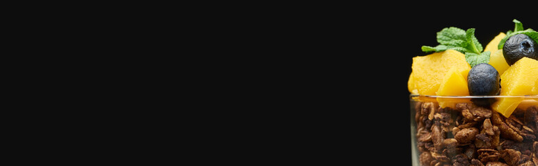 fresh granola with canned peach, blueberries and chia seeds isolated on black, panoramic shot