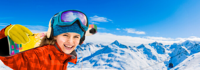 Young girl with ski in winter season, view from ski run at mountains and Val Thorens resort in sunny day in France, Alps.