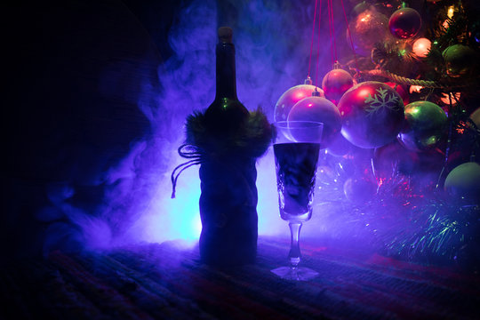 Red wine in crystal glass with bottle on colorful carpet with creative New Year artwork decorations. Copy space