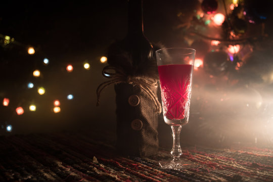 Red wine in crystal glass with bottle on colorful carpet with creative New Year artwork decorations. Copy space