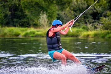 Girl wakeboarding on river lake sea on summer spring day in jacket