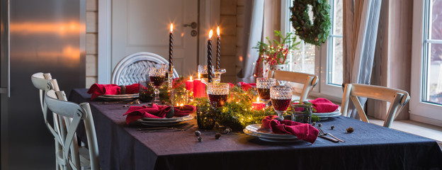Table served for Christmas dinner, festive setting with decorations, burning candles and fir-tree...