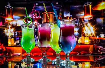 Cocktail glass splashing on dark toned smoky background or colorful cocktail in glass. Party club entertainment. Mixed light. Selective focus