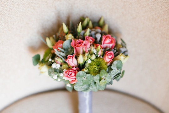 Bride bouquet of eucalyptus leaves, roses and eustom on beige background. Accessory for the bride at the wedding