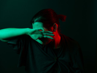 Junge Frau verbirgt Gesicht hinter der Hand und wendet sich ab