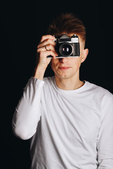 Cheerful guy with a retro camera on a black background