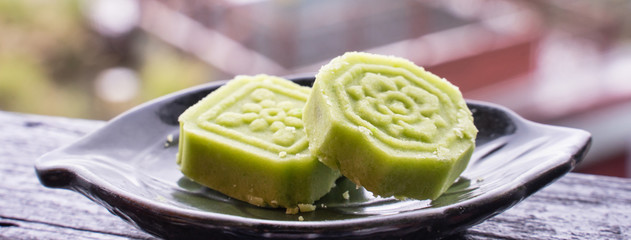 Delicious green mung bean cake with black tea plate on wooden railing of a teahouse in Taiwan with...