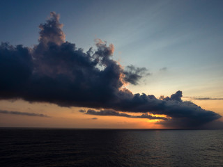 Naklejka na ściany i meble Sunset with dark cloudy sky in the sea