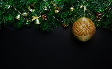 Christmas wreath decorated with a Big golden ball of beads and bells, cones, beads on a black background