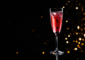 Glass of red champagne with ice on black background