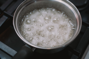 Boiling and boiling water and sugar in a pan on the stove. Cooking salted caramel at home. The recipe for homemade caramel and burnt sugar