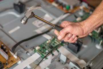 a man with a hammer and a wrench in his hands is in front of the TV, which shows the settings table