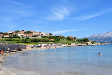 Fototapeta premium Locals and tourists enjoying a beautiful summer day along the sandy beaches of Lumbarda Beach on Korcula Island, Croatia