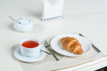Fruit tea and delicious fresh croissant on the table in a cozy coffee shop