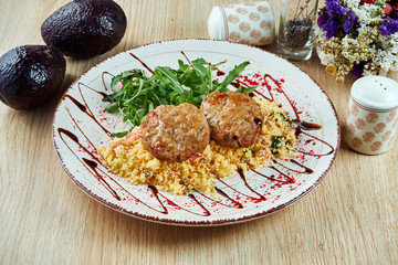 Turkey cutlets (burgers) with couscous garnish and pomegranate sauce on a white plate. Diet fitness nutrition. Healthy food. Close up view