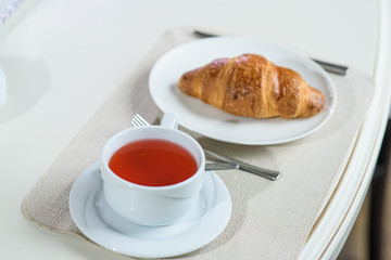Fruit tea and delicious fresh croissant on the table in a cozy coffee shop