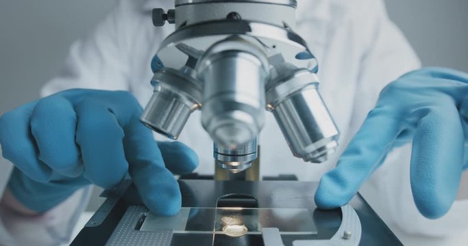 Close up shot of the scientist studies examining of test sample under the microscope in laboratory.