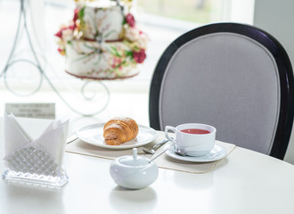 Fruit tea and delicious fresh croissant on the table in a cozy coffee shop