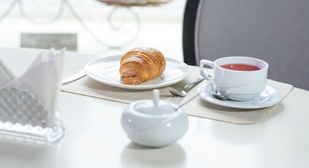 Fruit tea and delicious fresh croissant on the table in a cozy coffee shop