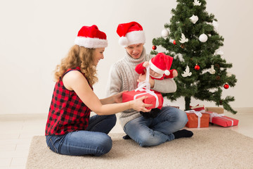Happy couple with baby celebrating Christmas together at home.