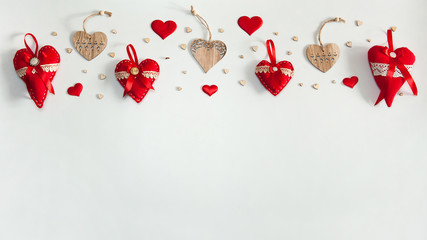 The Concept Of Valentine's Day. The border is made of wooden hearts and red decorative textile hearts sewn by hand on a white background.