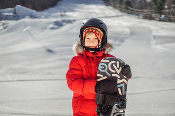 Little cute boy is ready for snowboarding. Activities for children in winter. Children's winter sport. Lifestyle
