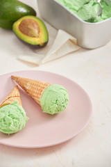 Obraz na płótnie Canvas Green avocado ice cream scoops in wafle cones on white background. Copy space