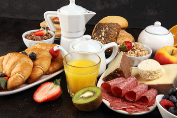 Fototapeta na wymiar Breakfast served with coffee, orange juice, croissants, cereals and fruits. Balanced diet. Continental breakfast with granola and fruits