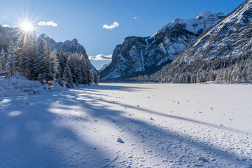 landscape photography on cold winter morning at sunrise at partly frozen Lago Dobbiaco, Dolomites, Three Peaks Dolomites, South Tyrol, Italy