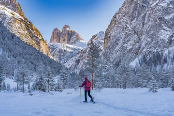 Fototapeta na wymiar active senior woman snowshoeing in spectacular Hoehlenstein Valley under the famous Three Peaks, Dolomites near village of Toblach, South Tyrol, Italy