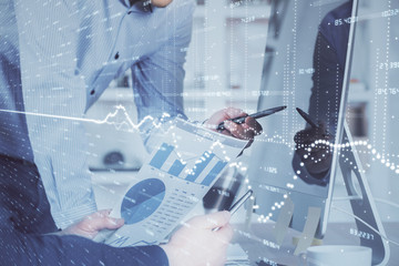 Double exposure of chart with businessman typing on computer in office on background. Concept of...