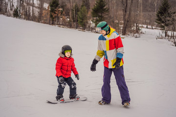 Snowboard instructor teaches a boy to snowboarding. Activities for children in winter. Children's winter sport. Lifestyle