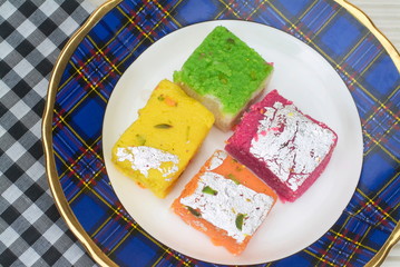 Four assorted barfi kept on a plate. 