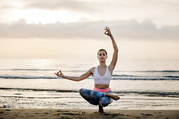 Fototapeta na wymiar yoga girl on the beach near the ocean at dawn