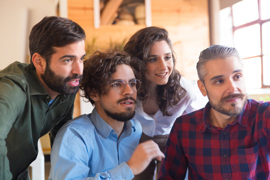 Team leader showing something away to impressed excited colleagues. Business colleagues in casual meeting in contemporary office space. Teamwork concept