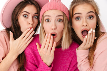 Portrait closeup of three amazed girls wondering and looking at camera