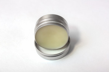 Lip balm in the round metallic tins on the white background
