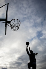 Chica jugando a baloncesto a contraluz