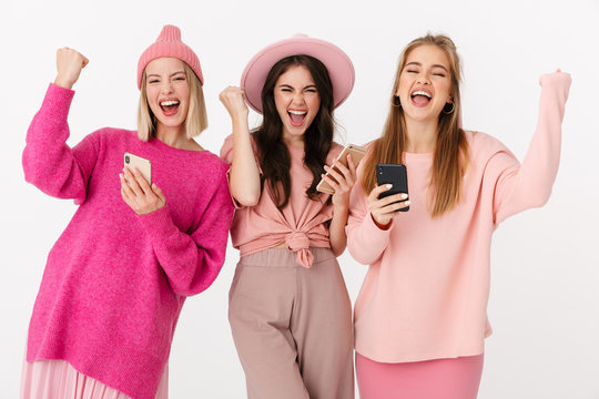 Image of three girls wearing pink clothes rejoicing and holding cellphones