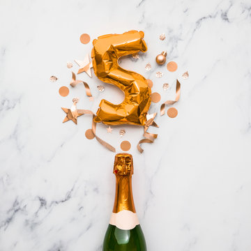 Champagne bottle with gold number 5 balloon. Minimal party anniversary concept