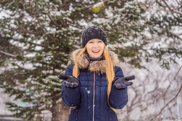 Fototapeta na wymiar Young woman enjoys a winter snowy day in a snowy forest
